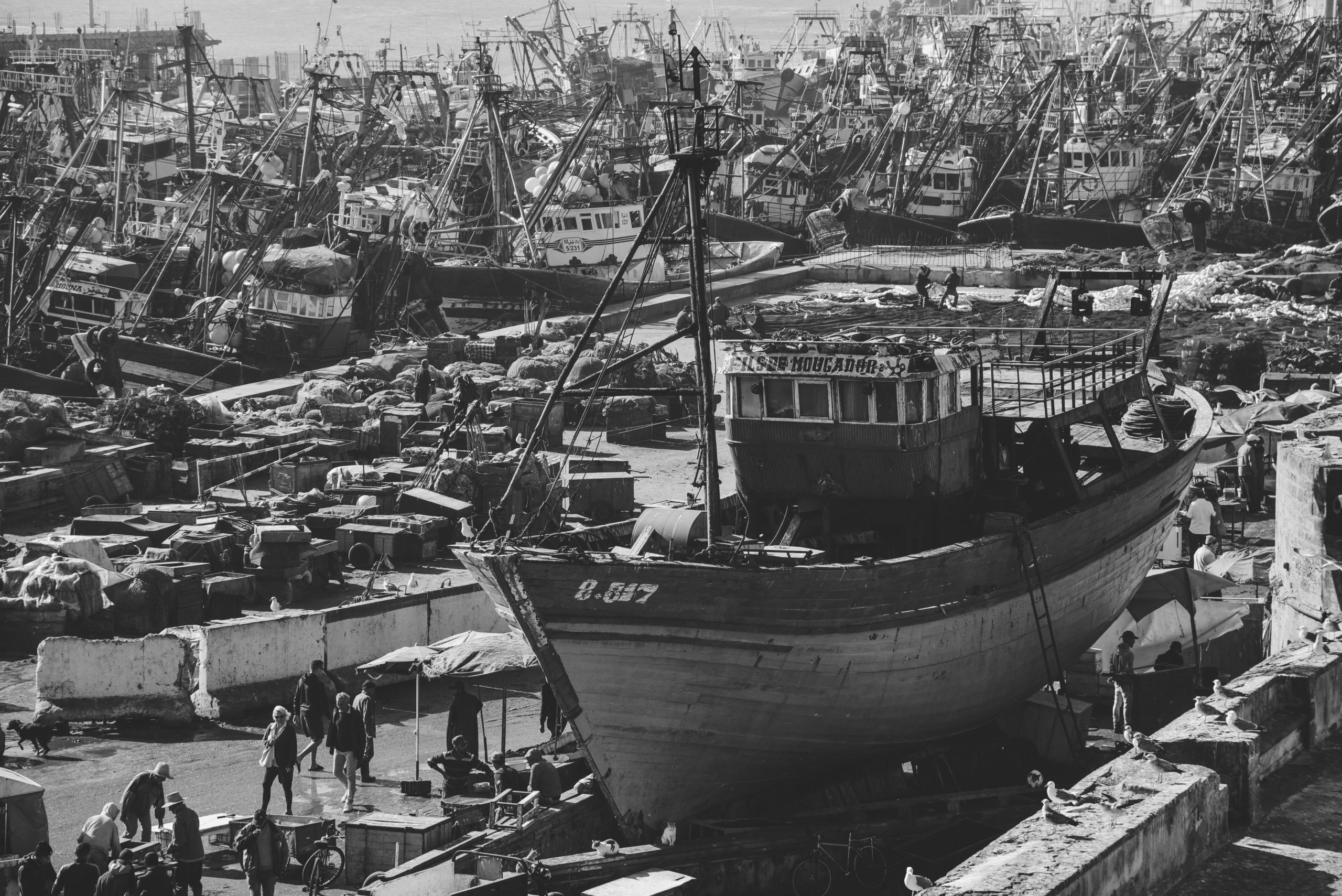 Black and white photo of a bustling shipyard in Essaouira, Morocco, showcasing fishing boats.